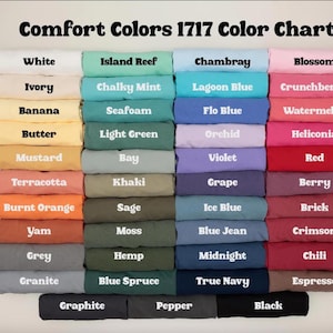 K&ouml;nnte beinhalten: Eine Comfort Colors 1717 Farbkarte mit achtundvierzig gefalteten T-Shirts in einem Raster. Jedes T-Shirt ist mit seinem spezifischen Farbnamen beschriftet, von Wei&szlig;-, Elfenbein- und Gelbt&ouml;nen bis hin zu verschiedenen Blau-, Gr&uuml;n-, Rosa-, Rot- und dunklen Neutralt&ouml;nen.