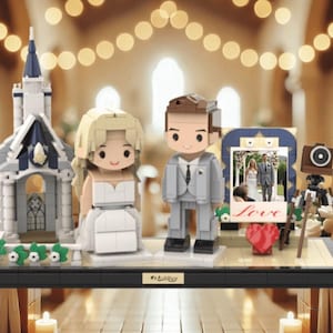 May include: A Lego wedding scene with bride and groom figures, a church, and a photo frame displaying a wedding photo. Includes a red heart, a vintage camera, and the word "Love". The figures are on a black base.