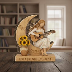May include: Wooden figurine of a girl playing a guitar, seated on a crescent moon with musical notes. A vase of sunflowers sits below. The base reads "JUST A GIRL WHO LOVES MUSIC".