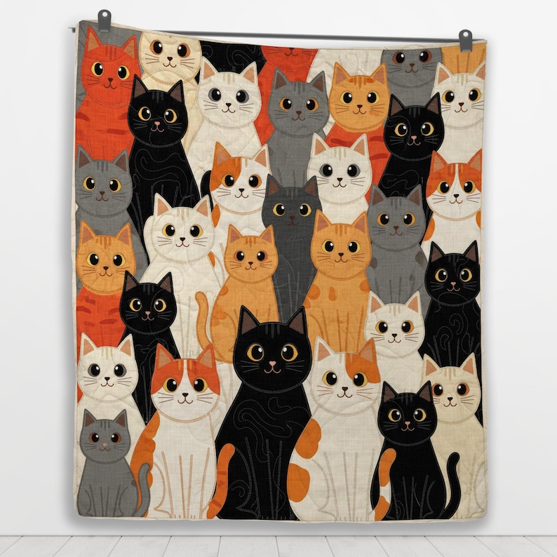 May include: A rectangular quilt featuring a repeating pattern of various cats in shades of orange, black, white, and gray. The cats are depicted with large eyes and simple facial features, arranged in a dense, overlapping grid across the fabric.