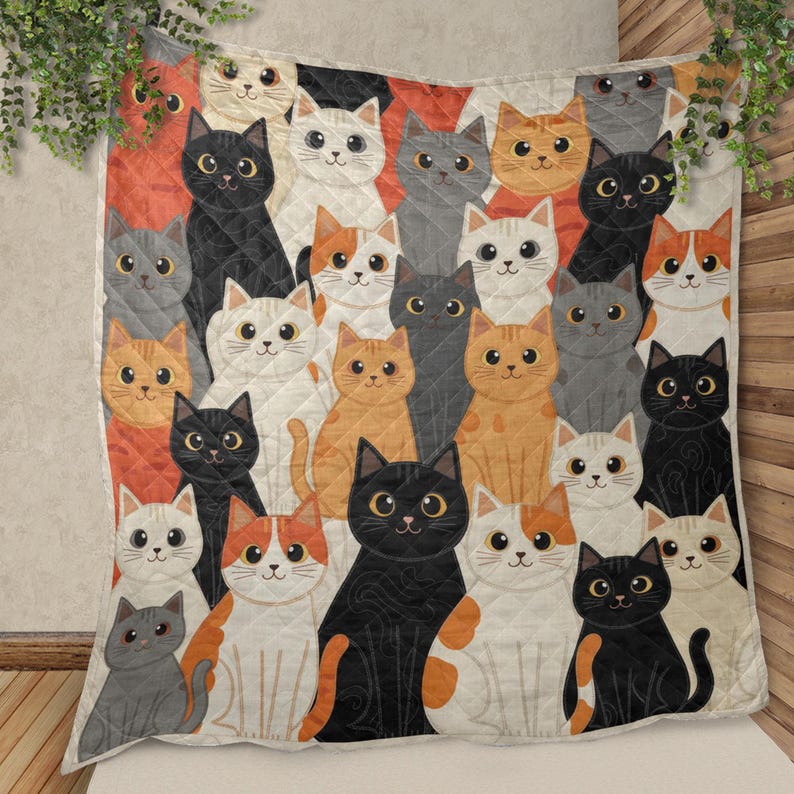 May include: A quilted throw blanket featuring a repeating pattern of illustrated cats in various colors including black, white, gray, orange, and calico. Each cat has large, expressive eyes and is depicted in a seated position across the fabric.
