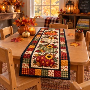 May include: A rectangular quilted table runner featuring a central panel with four pumpkins decorated with sunflowers and autumn leaves, surrounded by a border of patchwork squares in plaid and leaf patterns in shades of orange, red, and green.