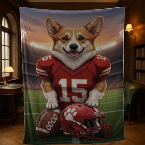 Puede incluir: Una manta de felpa con un corgi sonriente con una camiseta de f&uacute;tbol roja con el n&uacute;mero 15. El corgi est&aacute; de pie sobre un bal&oacute;n de f&uacute;tbol y un casco rojo. El fondo representa un estadio de f&uacute;tbol.