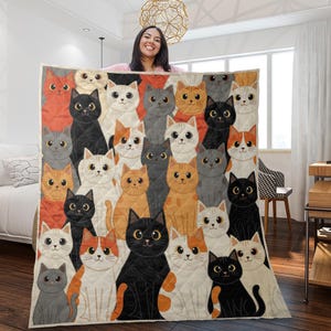May include: A rectangular quilt featuring a repeating pattern of illustrated cats in various colors including black, white, orange, and gray. Each cat has large, expressive eyes and is arranged in a dense, overlapping grid across the fabric surface.