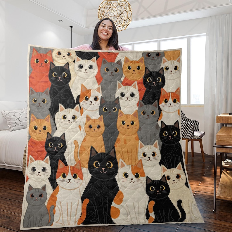 May include: A rectangular quilt featuring a repeating pattern of illustrated cats in various colors including black, white, orange, and gray. Each cat has large, expressive eyes and is arranged in a dense, overlapping grid across the fabric surface.