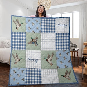 May include: A patchwork quilt with a duck design. The quilt features squares with blue gingham, duck illustrations, and a light blue background with flying ducks. The name "Harry" is written on the quilt.