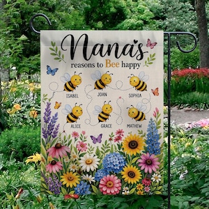 Pode incluir: Uma bandeira de jardim com o texto "Nana's reasons to Bee happy" e os nomes Isabel, Joan, Sophia, Alice, Grace e Mathew. A bandeira apresenta abelhas de desenho animado, borboletas e uma borda floral com girassóis, margaridas e outras flores.