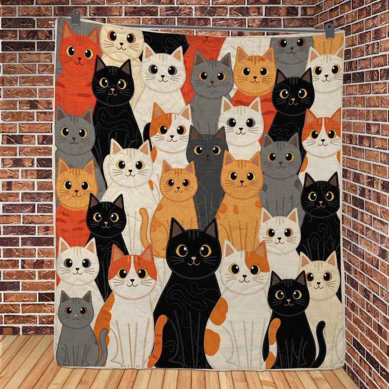 May include: A quilted blanket featuring a repeating pattern of cartoon cats in various colors including black, white, orange, and gray. Each cat has large eyes and a simple facial expression, arranged in a dense, overlapping grid across the fabric.