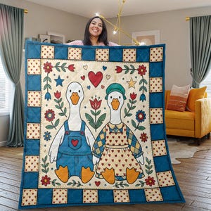 Pode incluir: Um cobertor acolchoado com um design lúdico com dois gansos vestidos com macacão e um vestido, de mãos dadas. O cobertor tem uma borda azul com padrões de corações e quadrados, e é decorado com flores, corações e estrelas. O esquema de cores é creme, azul, vermelho e amarelo.