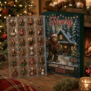 May include: A 2026 advent calendar featuring a large box with the name Henry and a Bigfoot illustration, alongside a clear plastic tray containing twenty-four small Bigfoot figurines in various holiday-themed poses and outfits.