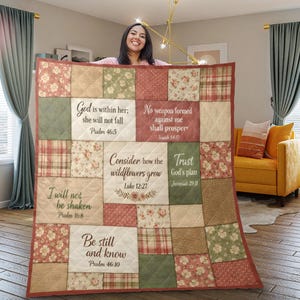 May include: A patchwork quilt with floral, plaid, and solid fabric patterns in red, green, and beige. The quilt features Bible verses. The quilt is displayed by a person.