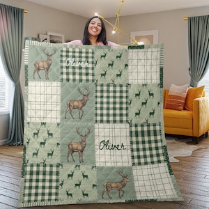 Könnte beinhalten: Eine gesteppte Decke mit Patchwork-Design in Salbeigrün und Weiß. Das Muster wechselt zwischen Quadraten mit Hirschillustrationen, grün-weißem Karomuster und Gittermustern. Der Name Oliver ist zweimal auf der Decke aufgedruckt.