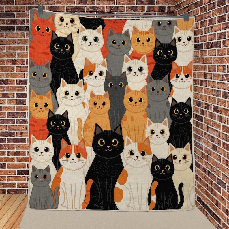 May include: A rectangular quilt featuring a repeating pattern of cartoon cats in various colors including orange, black, gray, white, and calico. Each cat has large, wide-set eyes and a simple facial expression, arranged in a dense, overlapping grid layout.