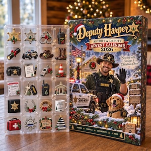 May include: A Deputy Harper Sheriff & Deputy Advent Calendar 2026 box featuring a sheriff and a dog in a snowy scene, alongside a clear plastic tray containing twenty-four miniature law enforcement-themed ornaments including badges, handcuffs, and a radio.