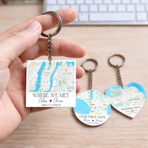May include: Three keyrings with map designs. One square keyring reads "WHERE WE MET" with names and coordinates. Two heart and circle-shaped keyrings feature map designs and text: "OUR FIRST DATE" and "WEDDING DATE".