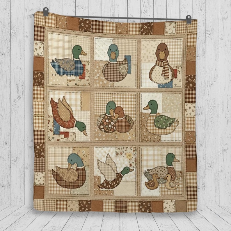 Puede incluir: Una colcha de patchwork con nueve paneles cuadrados, cada uno con una ilustraci&oacute;n de pato diferente en tonos marr&oacute;n, beige y crema. La colcha est&aacute; bordeada por un patr&oacute;n de cuadros marr&oacute;n y beige, con diversas texturas y estampados.
