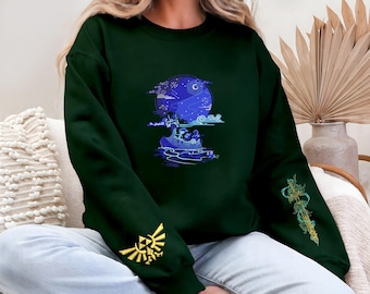 May include: Dark green sweatshirt featuring a blue and white graphic of a boat on water under a night sky. The left sleeve has a gold emblem, and the right sleeve has a gold and green design. The sweatshirt is a comfortable, casual style.