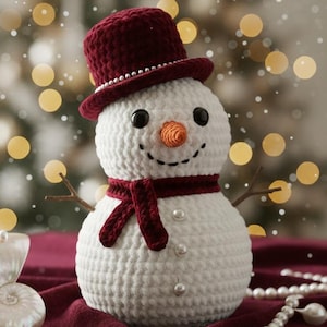 May include: A handmade crochet snowman with a burgundy top hat, scarf, and twig arms. The snowman has a carrot nose, black eyes, and a stitched smile. Decorative pearls are attached to the snowman and a seashell. Festive holiday decor.
