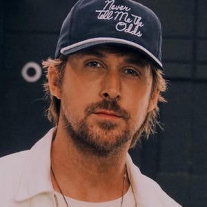 May include: A man with a beard and brown hair is wearing a white shirt and a blue baseball cap with the text "Never Tell Me The Odds" embroidered in white.