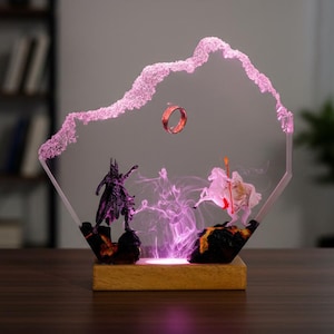 May include: A decorative resin sculpture featuring characters and elements from a fantasy story. The scene includes a floating ring, figures, and a light-up base. The sculpture is set against a neutral background, with a wooden base.