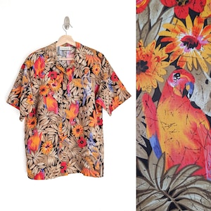 May include: A short-sleeve button-down shirt featuring a vibrant tropical print with red and orange parrots, yellow and orange flowers, and brown palm leaves on a black background. The shirt has a classic collar and a front button closure.