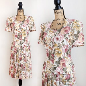 May include: A vintage floral print dress with a fitted bodice and a pleated skirt. The dress has a scoop neckline and short sleeves. The fabric is a lightweight, silky material.