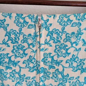 Pu&ograve; includere: Un vestito bianco con motivo floreale blu e chiusura a zip sul retro.