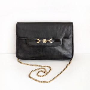Bolso de hombro vintage Morris Moskowitz de piel negra de los años 80 con decoración de bocado de caballo y correa de cadena dorada.