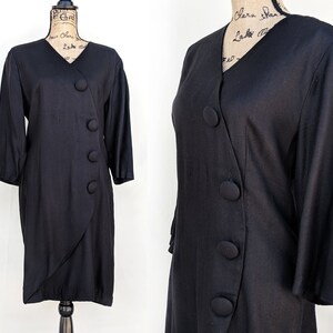 May include: A black long-sleeved dress with a wrap-style design and large black buttons down the front.