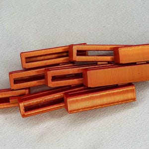 May include: A set of eight orange plastic rectangular blocks with a groove cut out of the center of each block.