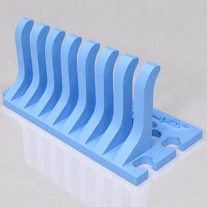 May include: A light blue, 3D-printed object with a series of curved, vertical supports. The supports are evenly spaced and rise from a rectangular base. The design suggests a rack or organizer.