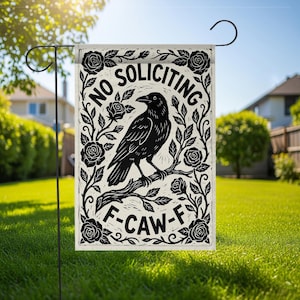 K&ouml;nnte beinhalten: Eine Gartenflagge mit einer schwarzen Kr&auml;he auf einem Ast, umgeben von Rosen und Bl&auml;ttern. Die Flagge tr&auml;gt die Aufschriften "NO SOLICITING" und "F-CAW-F" in einer dekorativen Schriftart. Die Flagge wird im Freien auf einem Metallst&auml;nder gezeigt.