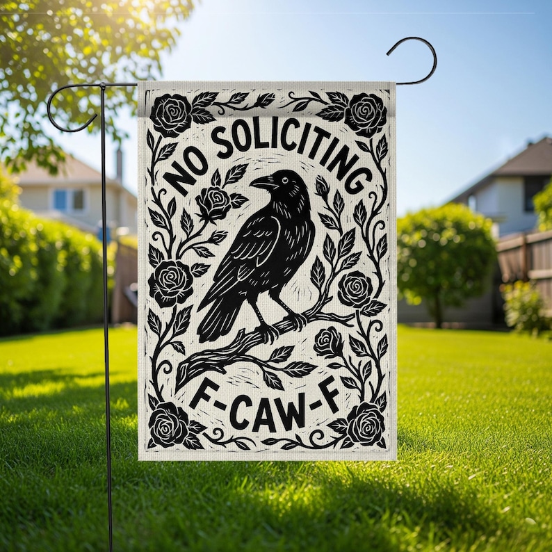 K&ouml;nnte beinhalten: Eine Gartenflagge mit einer schwarzen Kr&auml;he auf einem Ast, umgeben von Rosen und Bl&auml;ttern. Die Flagge tr&auml;gt die Aufschriften "NO SOLICITING" und "F-CAW-F" in einer dekorativen Schriftart. Die Flagge wird im Freien auf einem Metallst&auml;nder gezeigt.