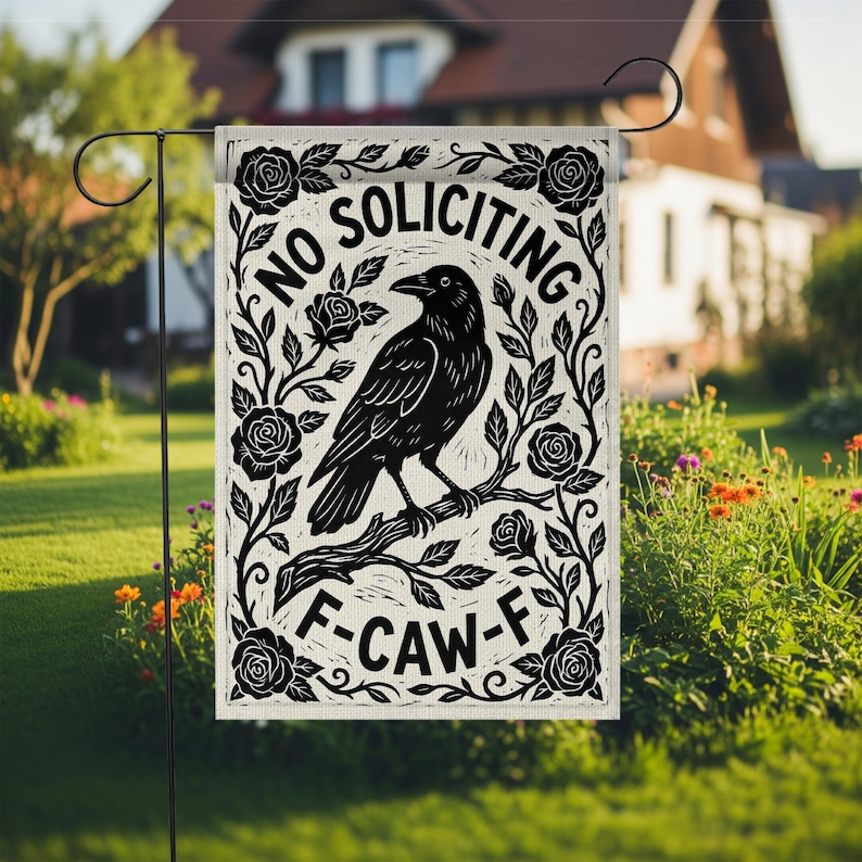 K&ouml;nnte beinhalten: Eine rechteckige Gartenflagge mit einem schwarz-wei&szlig;en Design. Die Flagge zeigt eine Kr&auml;he auf einem Ast, umgeben von Rosen und den Worten "NO SOLICITING" und "F-CAW-F". Die Flagge wird auf einem schwarzen Metallst&auml;nder in einem Garten gezeigt.