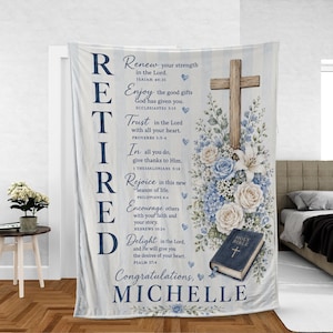 May include: A white and light blue striped fleece blanket featuring the vertical text RETIRED, the name MICHELLE, and several Bible verses. The design includes a wooden cross, blue and white floral arrangements, and a closed Holy Bible book.