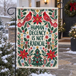 May include: A rectangular garden flag featuring the text "HUMAN DECENCY IS NOT RADICAL" in dark green letters. The design includes red cardinals, poinsettias, pine branches, holly berries, lit candles, ornaments, and a Christmas tree on a cream background.