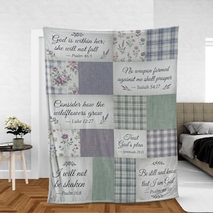 May include: A patchwork throw blanket featuring floral, plaid, and solid fabric squares in shades of blue, green, and purple. The blanket has inspirational quotes from the Bible printed on it, including "God is within her; she will not fall."