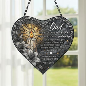 Può includere: Decorazione a forma di cuore per finestra commemorativa con catena nera. Il design presenta una candela accesa, gigli e la parola "Papà" con un messaggio sentito. La tavolozza dei colori include grigio, oro e bianco.