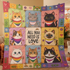 May include: A quilted blanket featuring nine squares, each with a different cartoon cat wearing a colorful scarf. The squares are bordered with hearts, stars, and flowers. The center square reads "ALL YOU NEED IS LOVE."