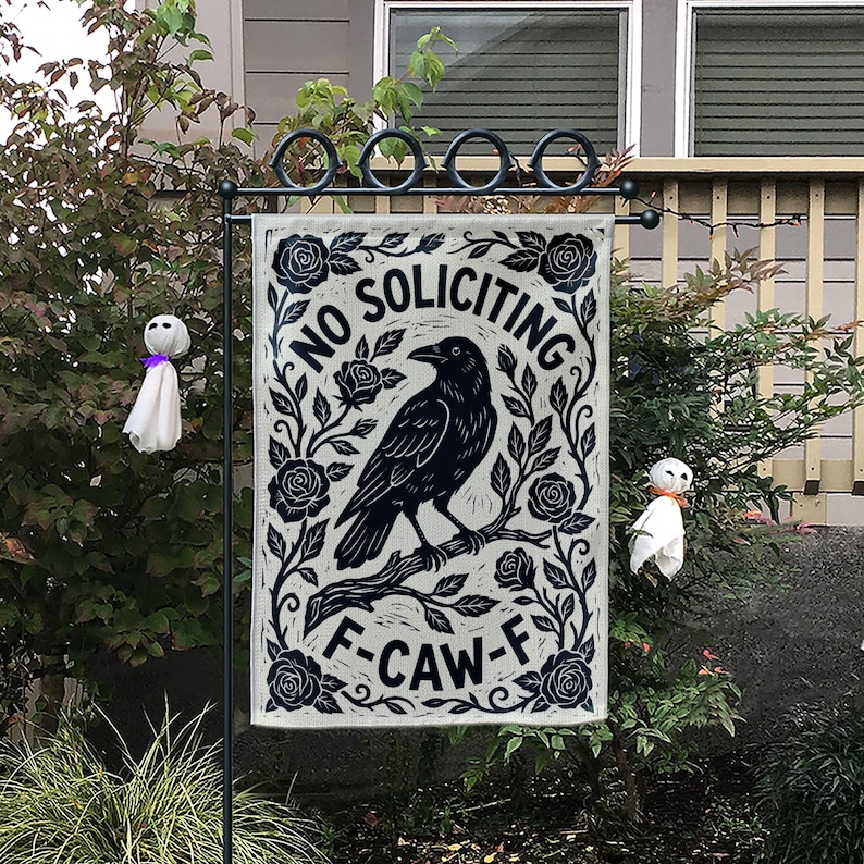 K&ouml;nnte beinhalten: Ein rechteckiger Gartenflagge mit einem schwarzen Raben auf einem Ast, umgeben von Rosen und dem Text "NO SOLICITING F-CAW-F". Die Flagge wird an einem schwarzen Metallst&auml;nder befestigt, mit zwei kleinen Geisterdekorationen.