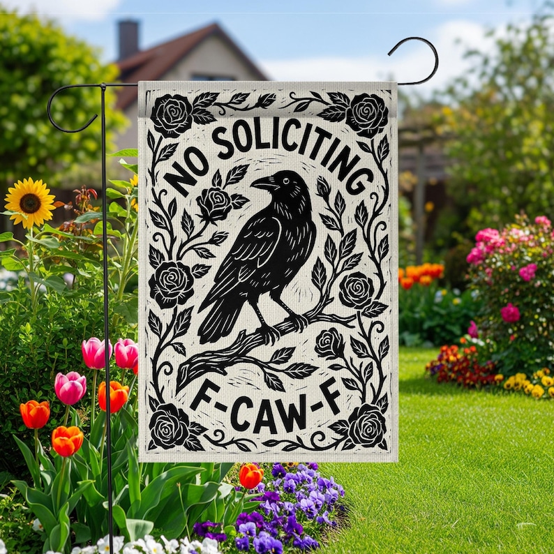 K&ouml;nnte beinhalten: Eine Gartenflagge mit einem schwarz-wei&szlig;en Design. Die Flagge zeigt eine Kr&auml;he auf einem Ast, umgeben von Rosen, mit den Worten "NO SOLICITING" und "F-CAW-F". Die Flagge wird in einem Garten mit Blumen gezeigt.