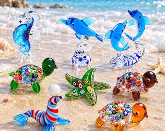 May include: A collection of glass animal figurines including a blue seahorse, two blue dolphins, a red, white, and blue striped seal balancing a white ball, a green starfish, and three turtles with colorful millefiori patterned shells.