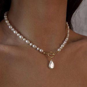 May include: A delicate pearl necklace with a gold clasp and a single large pearl pendant.