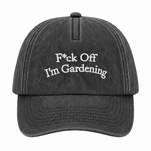 Peut inclure: Une casquette de baseball gris anthracite avec une texture d&eacute;lav&eacute;e et us&eacute;e. L'avant pr&eacute;sente un texte brod&eacute; en blanc qui indique F*ck Off I'm Gardening dans une police sans empattement. La casquette a une calotte structur&eacute;e et une visi&egrave;re.