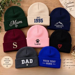 May include: A collection of nine knit beanies in various colours including dark green, beige, navy blue, maroon, pink, black, charcoal grey, and royal blue. Each beanie features embroidered text or symbols such as Mum, 1995, Adventure Awaits, S, Luna, a heart, Dad, and Your Text Here.