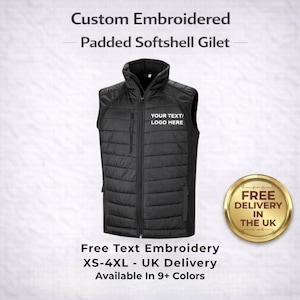 May include: Black padded softshell gilet with a high collar and a full-length zipper. The gilet has a pocket on the left chest and features the text "YOUR TEXT/LOGO HERE". The product is custom embroidered.