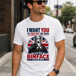 Op de afbeelding: Een wit T-shirt met korte mouwen en een afbeelding van een personage met een prullenbak als hoofd dat naar voren wijst. De tekst luidt I WANT YOU TO TAKE OUT THE TRASH, VOTE BINFACE en CLACTON 2026, tegen een cirkelvormig Union Jack vlagontwerp.