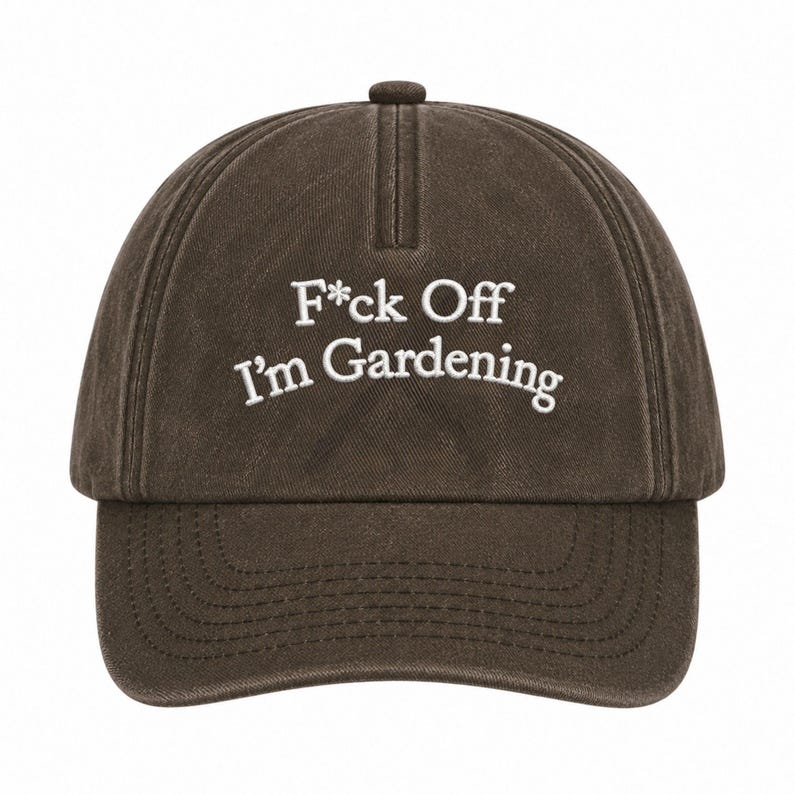 Peut inclure: Une casquette de baseball marron fonc&eacute; avec une finition d&eacute;lav&eacute;e et us&eacute;e. L'avant pr&eacute;sente un texte brod&eacute; en blanc qui indique F*ck Off I'm Gardening dans une police sans empattement. La casquette a une calotte structur&eacute;e et une visi&egrave;re courb&eacute;e.