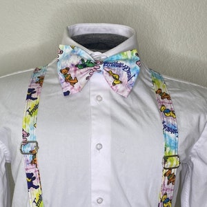 May include: A white button-down shirt with a tie-dye bow tie and suspenders. The bow tie and suspenders feature a tie-dye pattern with colorful bears and the text "grateful dead".