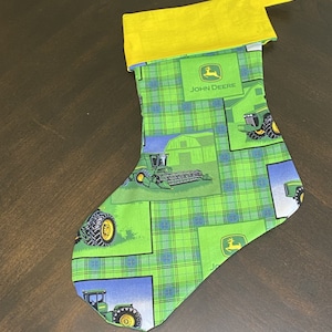May include: Green and yellow Christmas stocking with a John Deere logo and a tractor design.